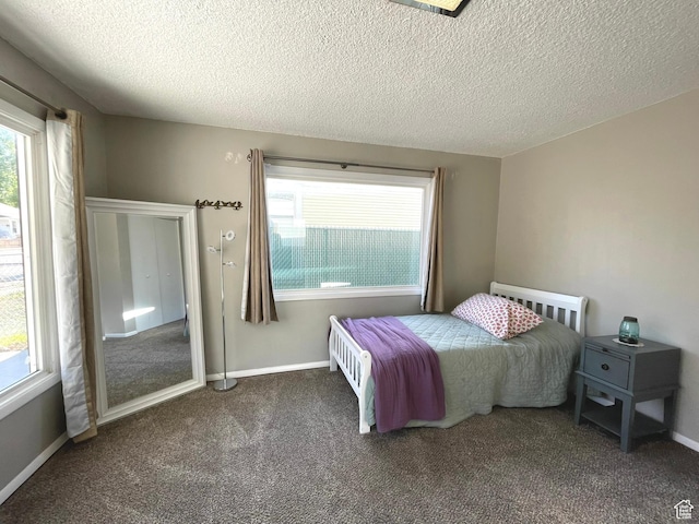 bedroom with multiple windows, carpet flooring, a textured ceiling, and baseboards