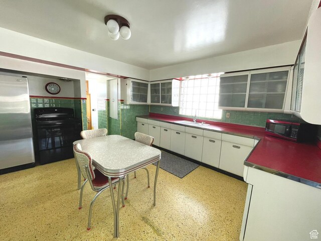 kitchen featuring black appliances, white cabinets, a sink, dark countertops, and decorative backsplash