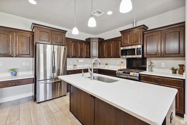 3335 W 2570 S, Hurricane, UT 84737 - kitchen with stainless steel appliances, a sink, decorative light fixtures, dark brown cabinets, and a center island with sink
