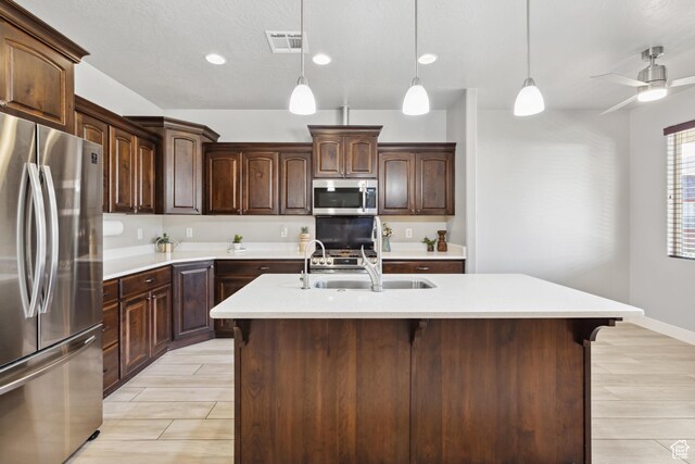 3335 W 2570 S, Hurricane, UT 84737 - kitchen with stainless steel appliances, light countertops, pendant lighting, dark brown cabinetry, and a sink