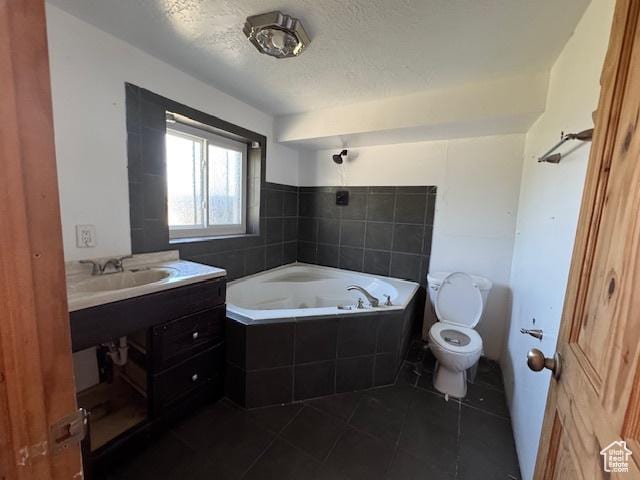bathroom with toilet, tiled tub, tile patterned flooring, a textured ceiling, and vanity