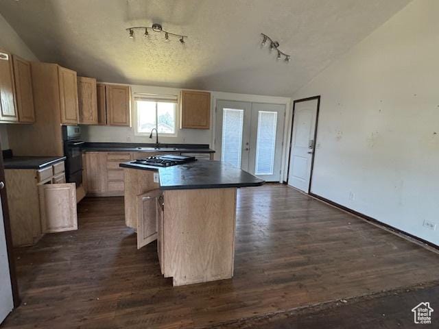 kitchen with lofted ceiling, a kitchen island, rail lighting, dark countertops, and dark wood-style floors