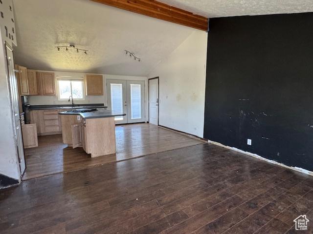 kitchen with light brown cabinets, a sink, dark countertops, dark wood finished floors, and a kitchen island
