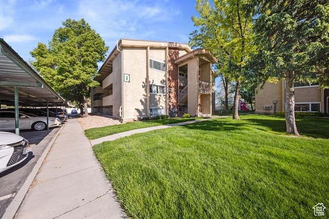 view of front of house featuring stucco siding, a front yard, and covered parking