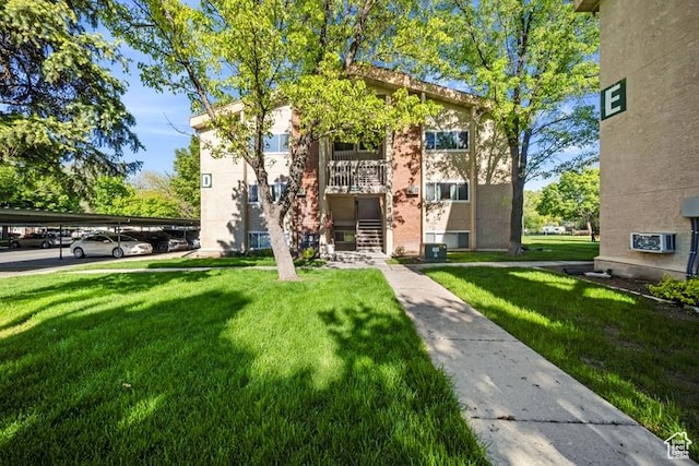 view of community featuring a lawn and covered parking