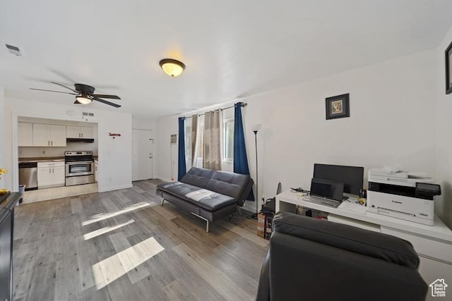 living room featuring wood finished floors, a ceiling fan, and baseboards