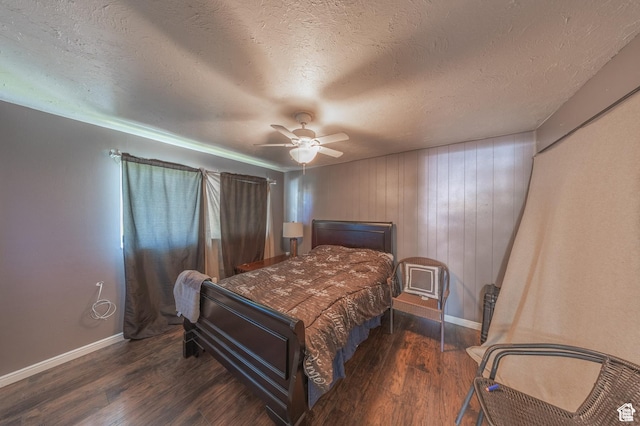 bedroom with baseboards, wood finished floors, ceiling fan, a textured ceiling, and wood walls