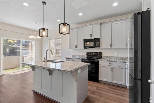 5621 W Stillwell Ln S, Herriman, UT 84096 - kitchen with black appliances, a sink, dark wood-type flooring, recessed lighting, and an island with sink