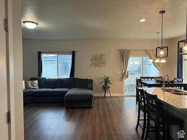 living area featuring a textured ceiling, dark wood-style flooring, healthy amount of natural light, baseboards, and recessed lighting