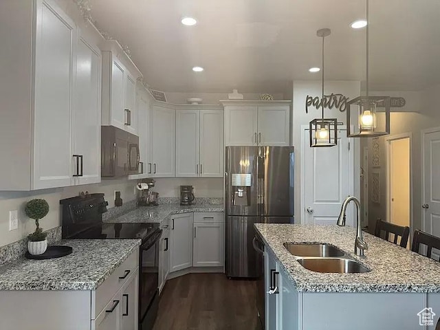 kitchen with black appliances, a sink, white cabinetry, a center island with sink, and light stone counters