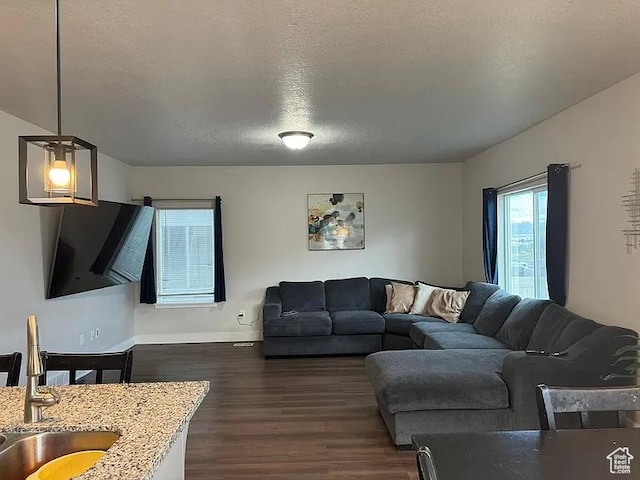 living area with dark wood-style flooring, baseboards, and a textured ceiling
