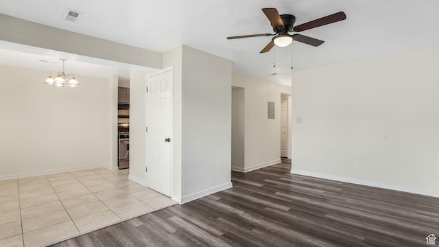 spare room featuring wood finished floors, a chandelier, a ceiling fan, and baseboards