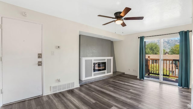unfurnished living room with wood finished floors, a ceiling fan, a glass covered fireplace, and baseboards