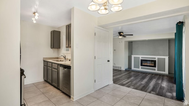 kitchen with stainless steel dishwasher, light tile patterned flooring, light countertops, and a sink
