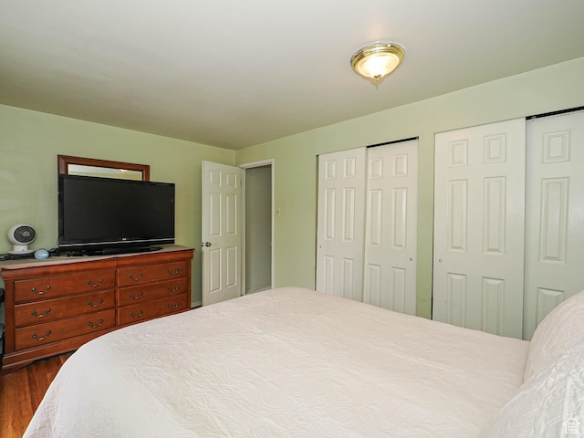 bedroom featuring multiple closets and dark wood-style flooring