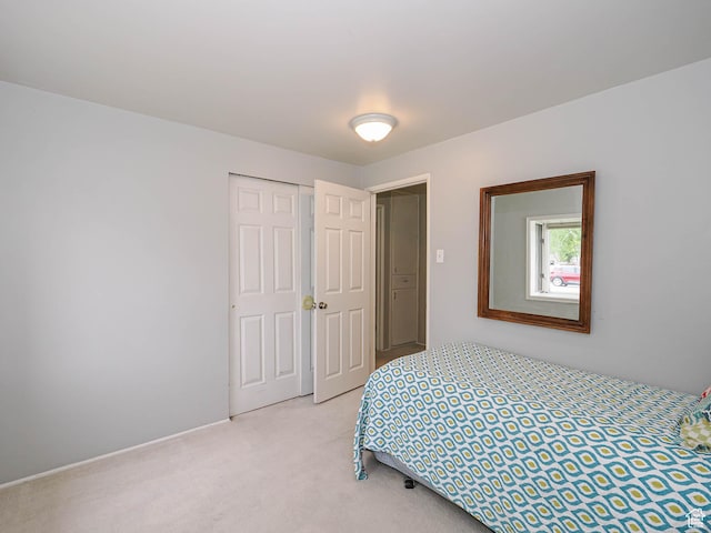 bedroom featuring light carpet, a closet, and baseboards