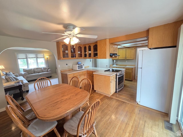 kitchen featuring white appliances, arched walkways, under cabinet range hood, light countertops, and a ceiling fan