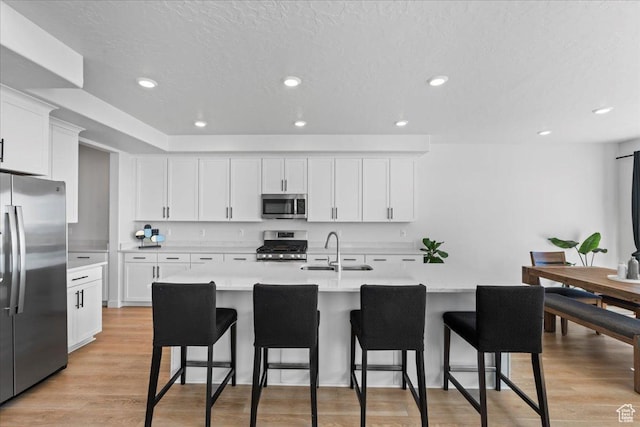 2102 S 2200 W, Woods Cross, UT 84087 - kitchen featuring appliances with stainless steel finishes, a sink, light countertops, a breakfast bar area, and white cabinets