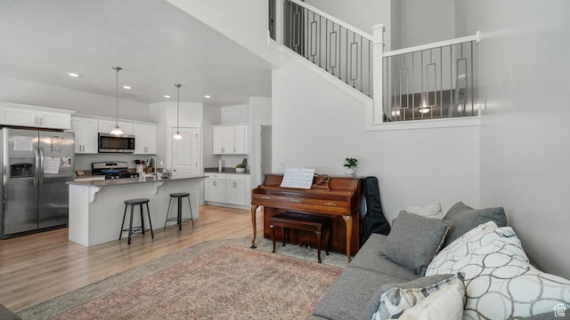 living room featuring light wood-type flooring, a towering ceiling, and recessed lighting