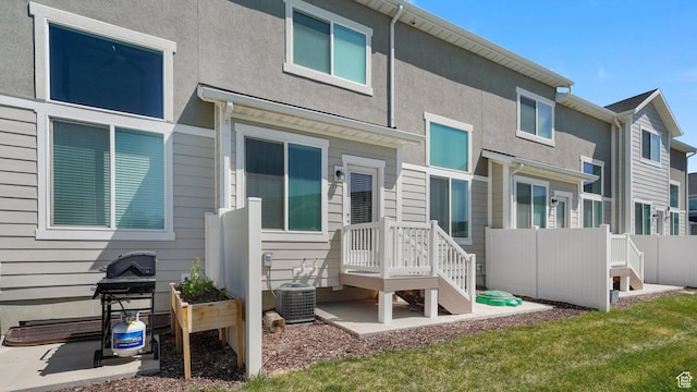 rear view of house with central AC unit and fence