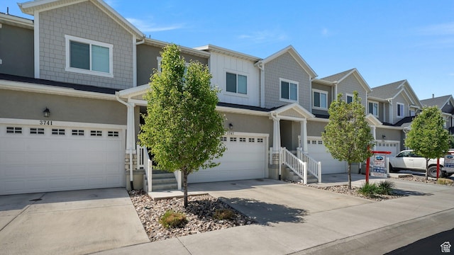 view of front of home featuring an attached garage, concrete driveway, stucco siding, and a residential view