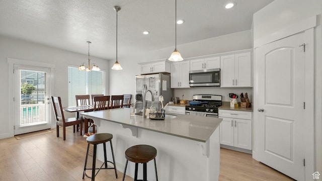 kitchen with stainless steel appliances, a kitchen breakfast bar, light wood-style flooring, recessed lighting, and white cabinetry