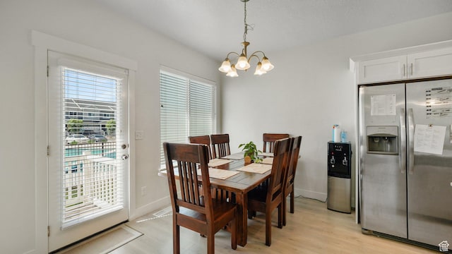 dining space featuring a chandelier, light wood-style floors, and baseboards