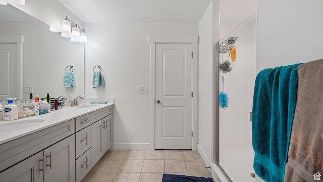 bathroom with tile patterned flooring, a shower stall, double vanity, and baseboards