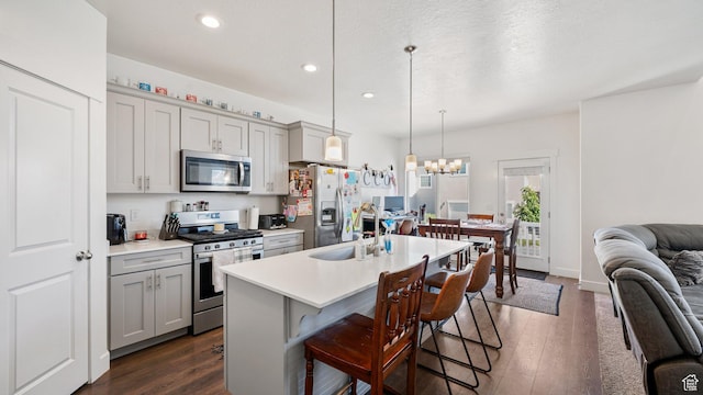 kitchen with stainless steel appliances, a sink, light countertops, gray cabinetry, and dark wood-style flooring