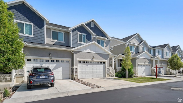 view of property featuring driveway, a residential view, stucco siding, a garage, and stone siding