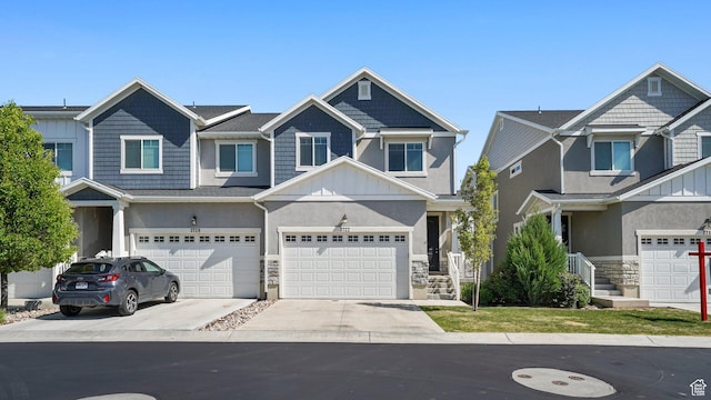 view of front of house with driveway, board and batten siding, stone siding, stucco siding, and an attached garage