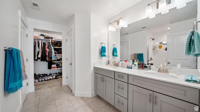 full bathroom with double vanity, tile patterned flooring, a spacious closet, and baseboards