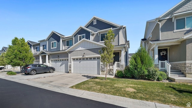 view of property featuring concrete driveway, a front lawn, stone siding, an attached garage, and board and batten siding