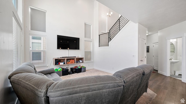 living room with a high ceiling, dark wood-style flooring, stairway, and baseboards