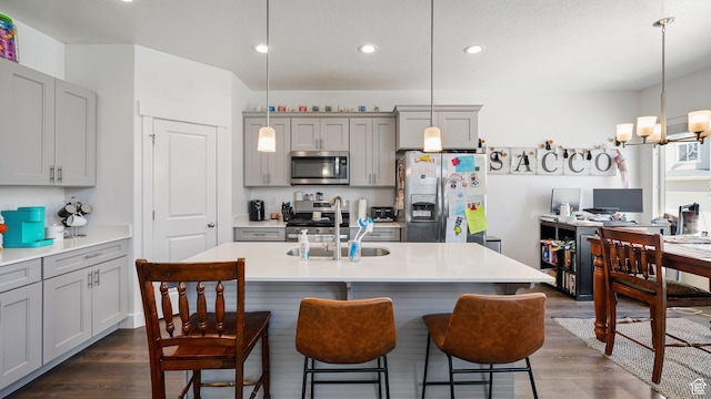 kitchen with stainless steel appliances, gray cabinetry, recessed lighting, dark wood finished floors, and light countertops