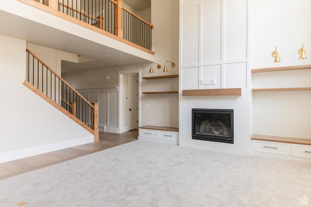 9856 N Sorrel Dr, Eagle Mountain, UT 84005 - unfurnished living room featuring carpet flooring, a high ceiling, stairway, and a fireplace