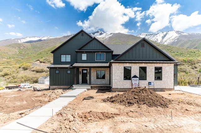 9856 N Sorrel Dr, Eagle Mountain, UT 84005 - view of front facade featuring board and batten siding, a mountain view, covered porch, and stone siding