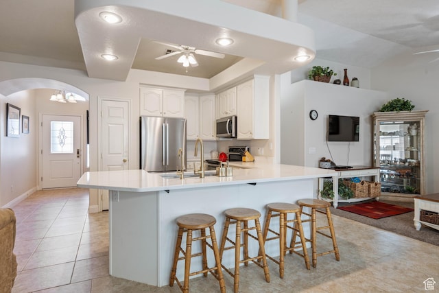 kitchen featuring stainless steel appliances, ceiling fan, arched walkways, a sink, and a peninsula