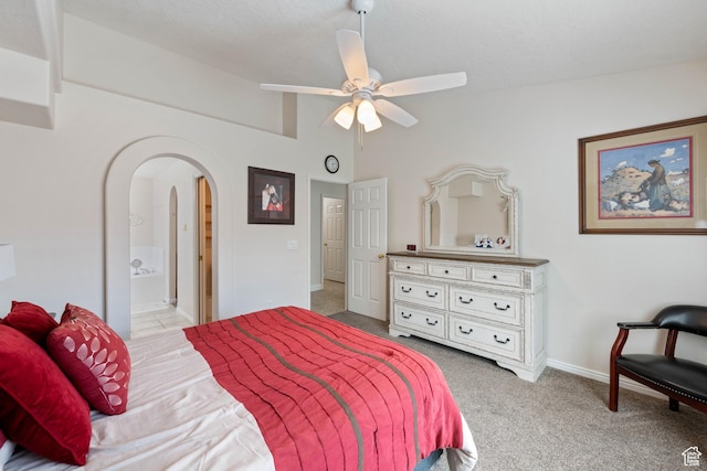 carpeted bedroom with arched walkways, baseboards, ensuite bathroom, and ceiling fan
