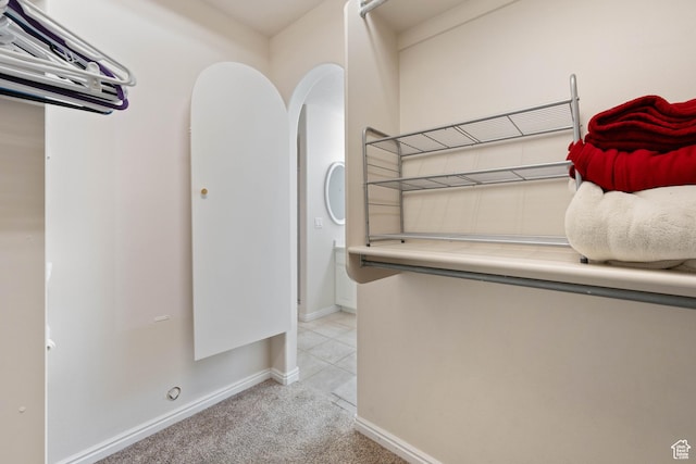 washroom with arched walkways, baseboards, and light colored carpet