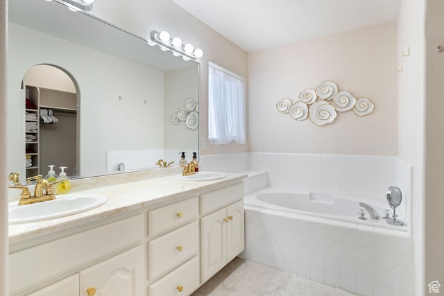full bath featuring a garden tub, double vanity, a walk in closet, and tile patterned flooring