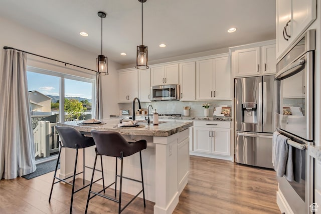 2217 W 650 S, Lehi, UT 84043 - kitchen with appliances with stainless steel finishes, recessed lighting, light stone countertops, white cabinetry, and an island with sink