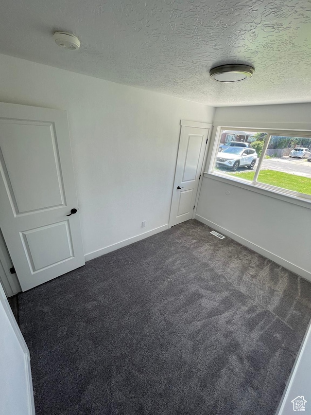 1426 W Carlos Dr S, West Valley City, UT 84119 - spare room with dark carpet, a smoke detector, baseboards, and a textured ceiling
