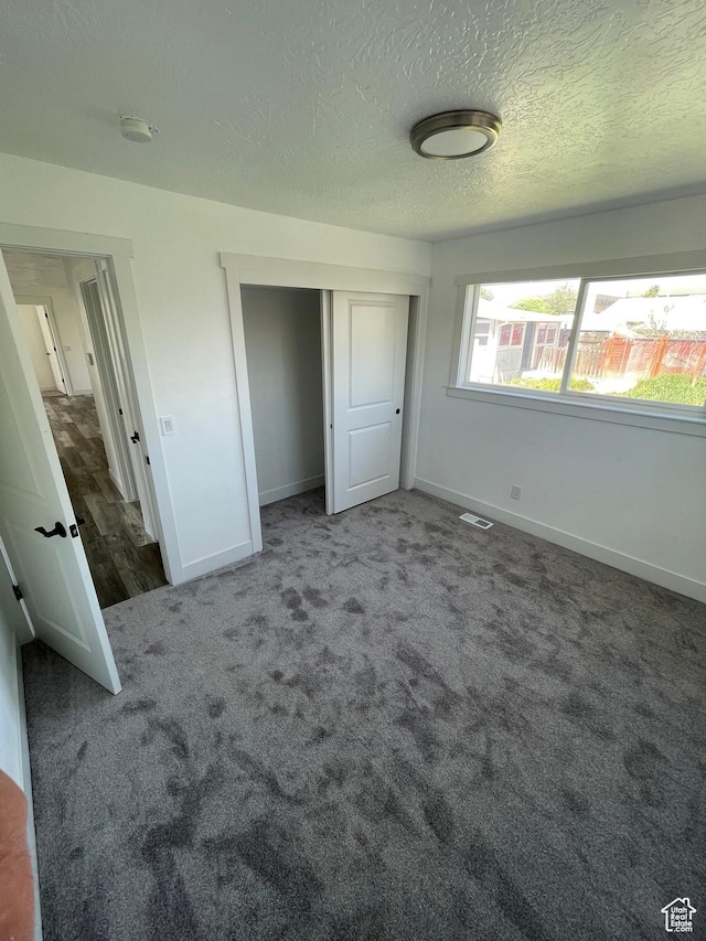 1426 W Carlos Dr S, West Valley City, UT 84119 - unfurnished bedroom with baseboards, carpet flooring, a closet, and a textured ceiling