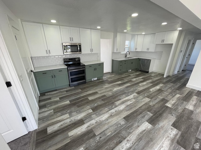 1426 W Carlos Dr S, West Valley City, UT 84119 - kitchen featuring appliances with stainless steel finishes, a sink, dark wood-type flooring, white cabinetry, and tasteful backsplash