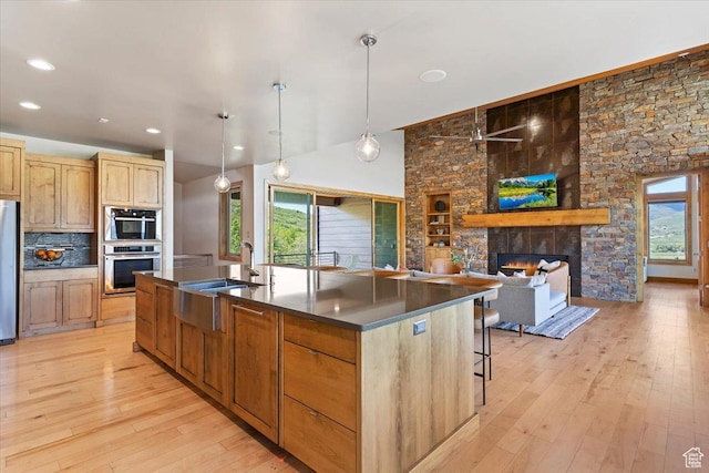 1108 N Lakeside Ct, Eden, UT 84310 - kitchen featuring dark countertops, light wood-type flooring, healthy amount of natural light, a fireplace, and vaulted ceiling