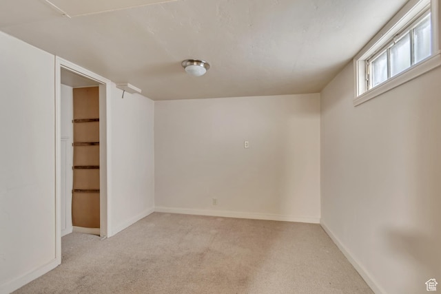below grade area featuring light carpet and baseboards