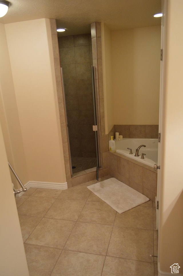 bathroom with a garden tub, a shower stall, tile patterned floors, and baseboards