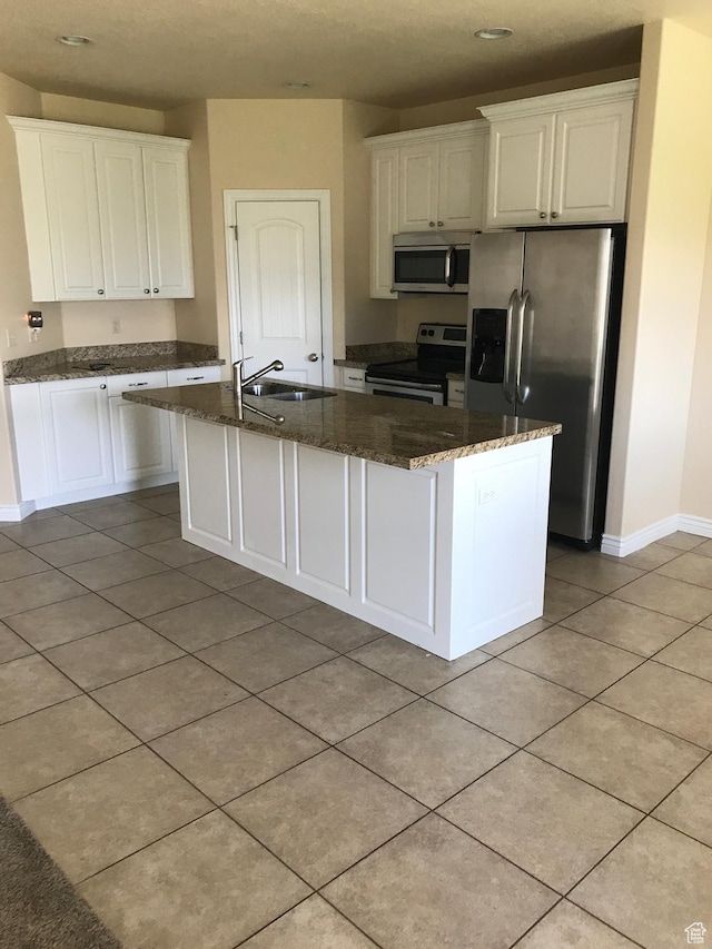 kitchen with appliances with stainless steel finishes, a sink, white cabinetry, baseboards, and light tile patterned floors