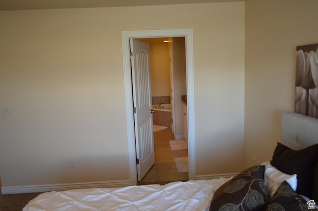 bedroom with baseboards, connected bathroom, and tile patterned flooring